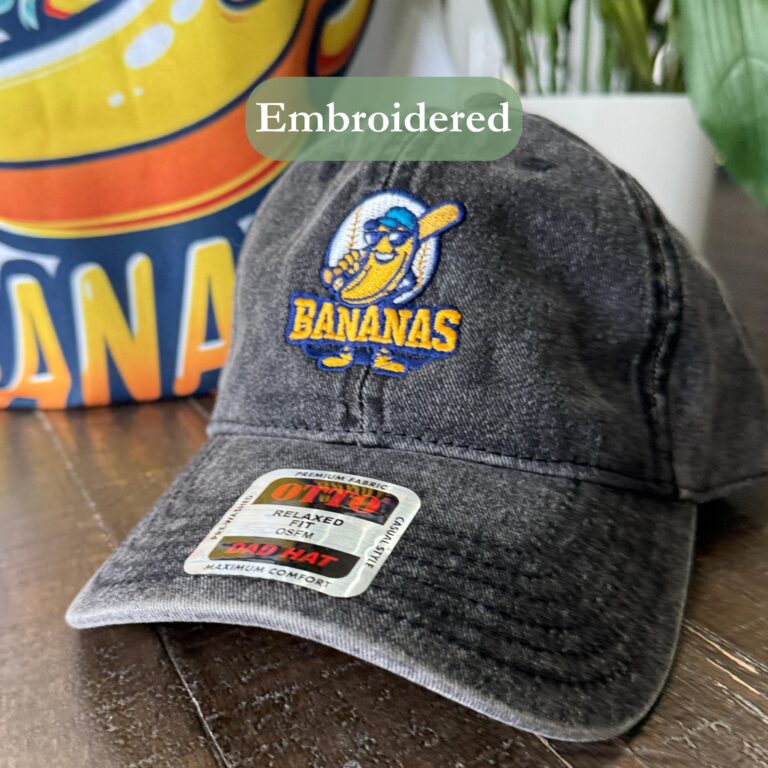 Front view of a vintage banana baseball cap with an embroidered banana character holding a baseball bat.