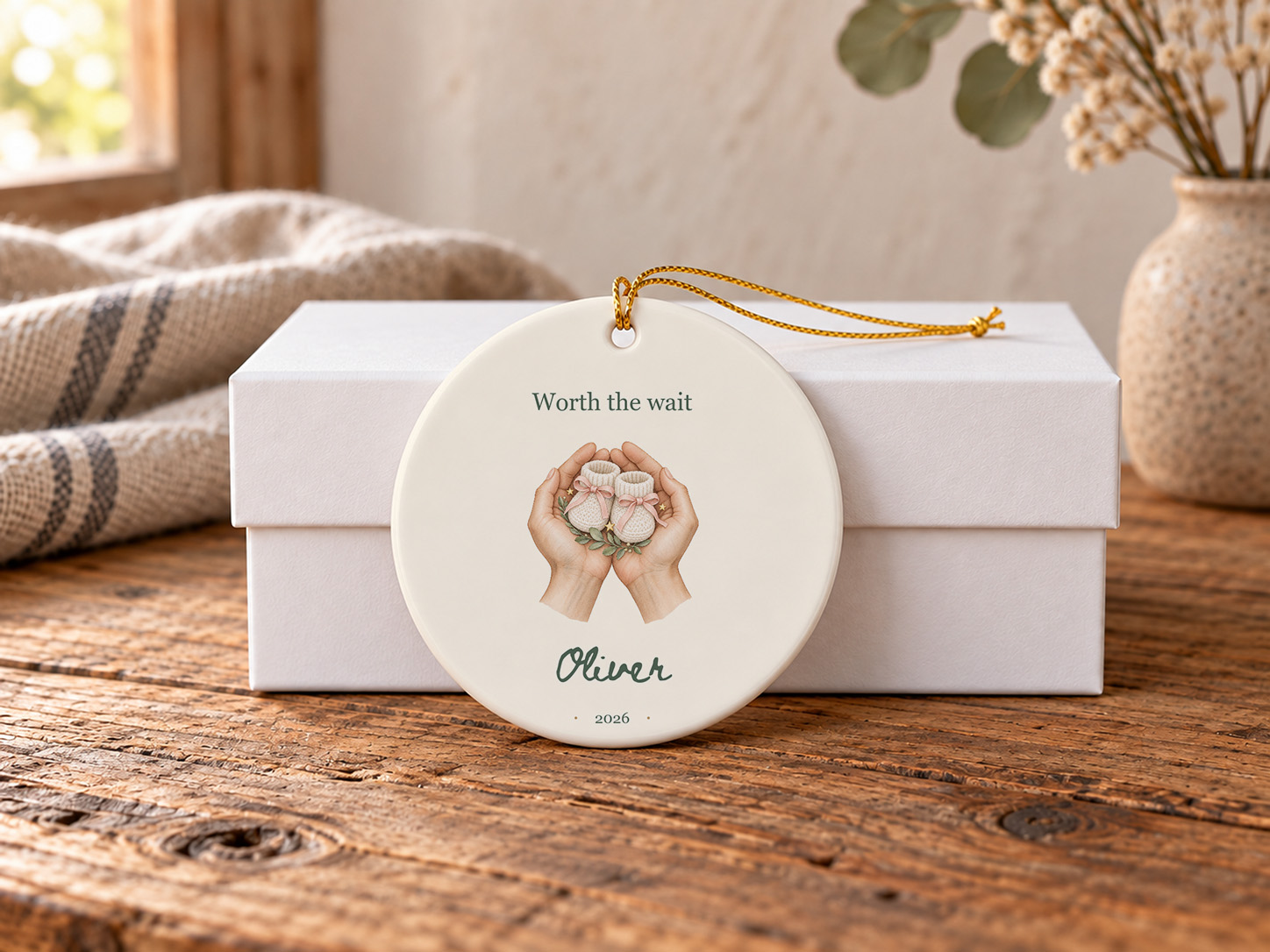 Personalized baby booties ornament with illustrated hands cradling baby booties and Worth the wait lettering